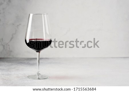 long-stemmed glass with red wine on a grey background - with space for text