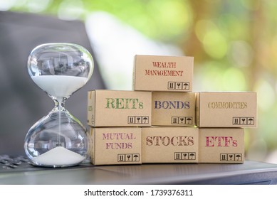 Long-term Online Asset Allocation / Sustainable Growth For Wealth Management Concept : Sandglass Clock, Boxes Of Financial Products E.g REITs, Bonds, Commodities, Mutual Funds, Stocks, ETFs On Laptop