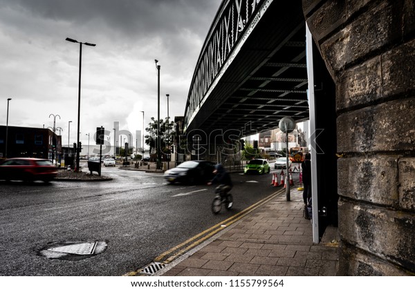Longton Railway bridge\
with a cyclist and traffic going by (Blurred people and cars, focus\
on the bridge)