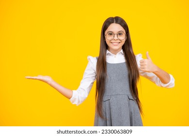 Look at advert. Teenager child points aside shows blank copy space for text promo idea presentation, poses against yellow background. - Shutterstock ID 2330063809