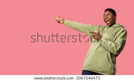 Look Aside. Excited Overweight African American Lady Pointing Fingers At Free Space For Text Advertisement Standing Over Pink Studio Background. Great Offer Concept. Panorama