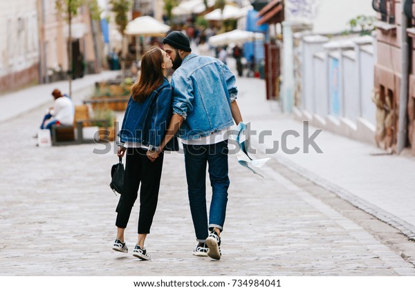 街を歩きながら手を組んで歩く2人の観光客を後ろから見る の写真素材 今すぐ編集