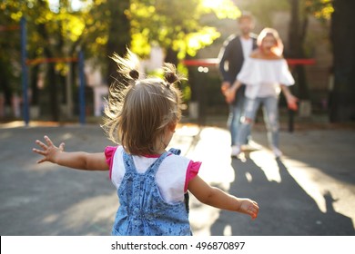 Look From Behind At Jazzy Child Running To Parents While They Wait For Her In The Park