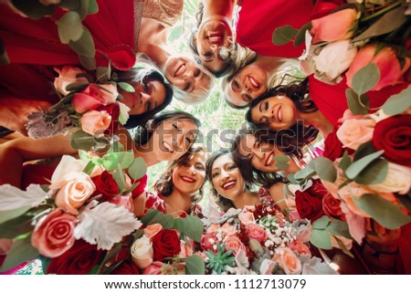 Look from below at gorgeous bride and pretty bridesmaids holding in their hands rose bouquets