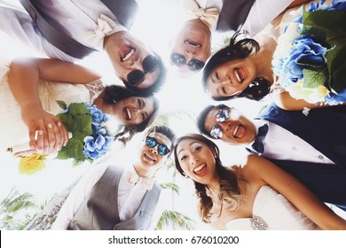 Look from below at newlyweds and friends hugging outside