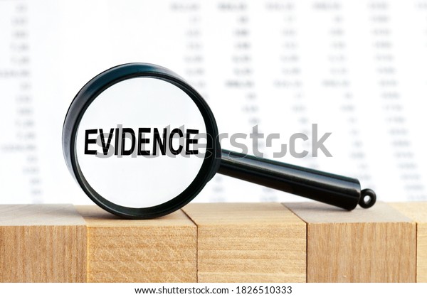 Look closely and Evidence with a magnifying\
glass. Looking through a magnifying glass at the word Evidence, a\
business concept. Magnifying glass on the background of columns of\
numbers.