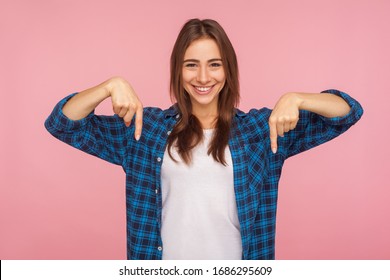 Look down, choose option below! Portrait of charming brunette girl in checkered shirt pointing down at place for advertisement, commercial content. indoor studio shot isolated on pink background - Shutterstock ID 1686295609