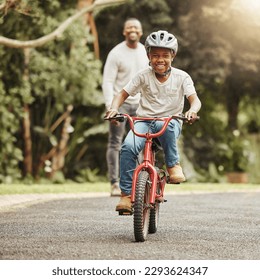 Look at him go. Shot of an adorable boy learning to ride a bicycle with his father outdoors. - Powered by Shutterstock