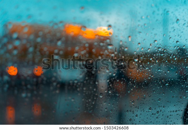Look on the water drops on car windshield\
from inside the car at rain on the city\
street