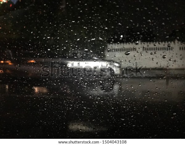 Look on wet city through\
windshield from inside the car at rain weather , Drop water on the\
glass car. 
