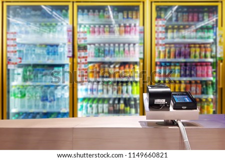 Look out from the payment counter, blur image of beverage cooler inside the convenience store as background.