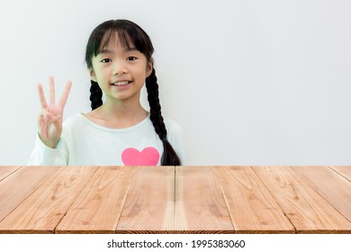 Look Out From The Table, Asian Girl Holding Up Three Fingers In The Background