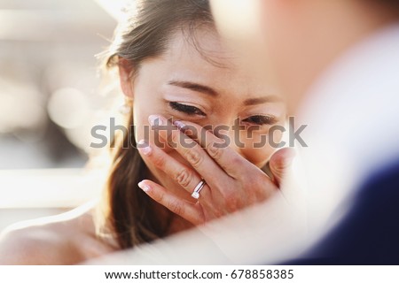 Look over groom's shoulder at happy crying bride