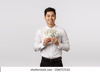 Look At That Cash. Handsome Happy And Rich Young Asian Guy Ready Spend Paycheck On Shopping, Holding Money And Smiling, Winning Sport Bid, Achieve Success Corporate Ladder, White Background