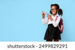 Look There. Black Elementary Student Girl Pointing Fingers At Copy Space Over Yellow Background. Panorama, Studio Shot