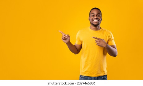 Look There. Cheerful African American Man Pointing Fingers Aside Showing Empty Space For Text Posing Smiling To Camera Over Yellow Background In Studio. Panorama - Shutterstock ID 2029465886