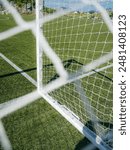 Look through net to football field in soccer stadium. Soccer field with green grass in football sport stadium behind net curtain. Sport equipment, football gate