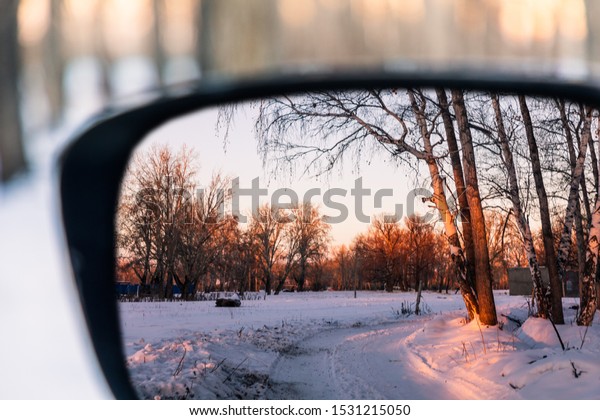 Look at the winter sunshine\
from the rearview mirror of the car, shining on the woods after the\
snow