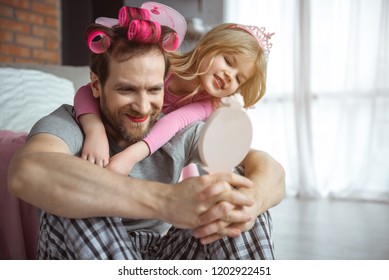 Look at you. Cheerful girl is showing her father his makeup and hairstyle. Dad is looking at his reflection with surprise and smiling - Powered by Shutterstock