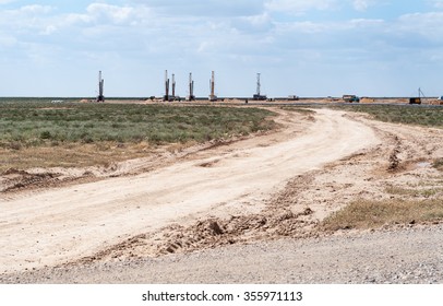 Looking across flat arid remote terrain to an operative drilling rig in Central Asia