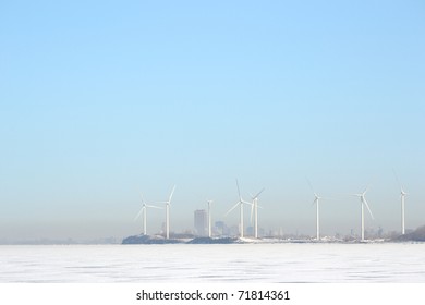 Looking Across A Frozen Lake Erie In Winter At A Group Of Windmills Along The Lake Erie Shoreline Near A Misty  Buffalo New York.