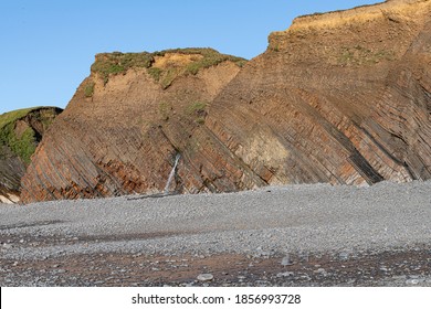 Looking Across Pebbly Beach To Sedimentary Rocks