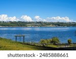 Looking across the Tacoma Narrows Strait from Tacoma Narrows Park in Washington on a sunny afternoon, with Mt. Rainier partly visible in the low clouds.