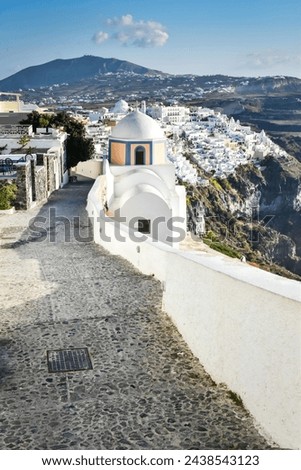 Looking across the town of Fira and the Catholic Church of Saint Stylianos on the Greek island of Santorini on the pathway at the edge of the caldera.