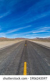 Looking Along A Long, Straight Road Through The Nevada Desert, With A Blue Sky Overhead