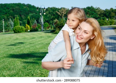 Looking Aside. Happy Mother Holding Little Joyful Child Behind Her Back.