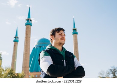 Looking Away Young Man 34 Years Old Against Muslim Mosque (Mashkhur Jusup Central Mosque) And Autumn Leaves Trees. Russian Migrant In Kazakhstan. Waist Up Lifestyle Travel Portrait, Religion Concept.