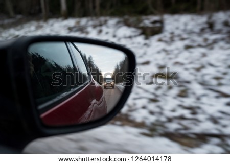 looking back in a side mirror at a car