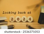 Looking back at the year 2024 concept on wooden chips and inscription. Best events of the year, highlights, review, performance, evaluation of 2024. Office desk background.