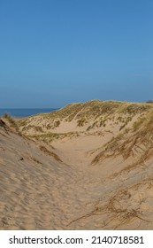 Looking between marram grass covered sand dunes towards the sea, at Formby in Merseyside
