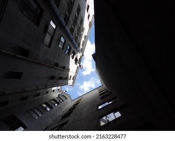 Looking up to the blue sky with clouds between buildings