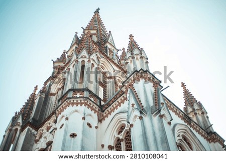Looking up at the breathtaking Neo-Gothic spires of Our Lady of Lourdes Church in Tiruchirappalli, Tamil Nadu. A stunning facsimile of the Basilica of Lourdes in France, beautifully built with indigenous craftsmanship.Symmetrical grandeur against the sky. The intricate detailing and soaring turrets of Trichy's historic Gothic Revival marvel