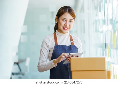 Looking camera, Startup small business SME, Entrepreneur owner using tablet taking receive and checking online purchase shopping order to preparing pack product box.