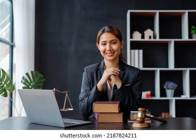 Looking camera. Young Attractive Asian female lawyer working in office with contract and law books when sitting at desk. Law, legal services, advice, Justice and real estate concept. - Shutterstock ID 2187824211
