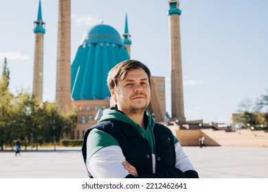 Looking At Camera Young Man 34 Years Old Against Muslim Mosque (Mashkhur Jusup Central Mosque) And Autumn Leaves Trees. Waist Up Lifestyle Travel Portrait, Religion And Trip Concept.