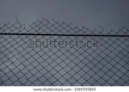 Looking up at a chain link fence with blue sky and clouds. wire fence. Chain link fence see sky. Opening in metallic fence. blue sky. Challenge. breakthrough concept.                                 