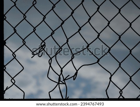 Looking up at a chain link fence with blue sky and clouds. wire fence. Chain link fence see sky. Opening in metallic fence. blue sky. Challenge. breakthrough concept.                      