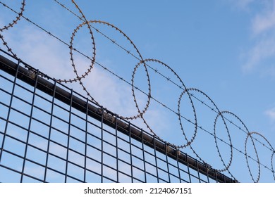 Looking up at circular barbed wire fence against blue sky diagonal juxtaposition