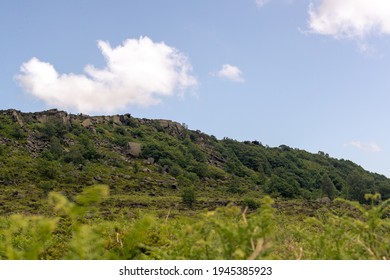 Looking Up To The Cliff Edge Of Curbar Edge, A Natural Formed Edge In The Peak District National Park. This Valley Was Created By Glaciers In The Last Ice Age But Now Is Full Of Trees And Plants.