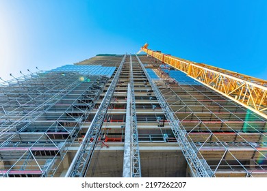 Looking Up At The Construction Site Of A High-rise Building With A Yellow Crane