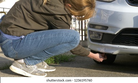Looking At A Damaged Vehicle. Woman Inspects Car Damage After An Accident