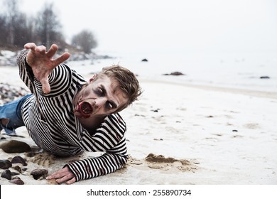 Looking dead man crawling on the seaside