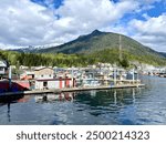 Looking at the dock and boats in the harbor in Ketchikan, Alaska, with green and snowy mountains in the background.