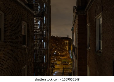 Looking down between to vintage brick buildings onto the street on an erie night with lights