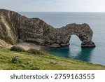Looking down from the coastal path at Durdle Door in Dorset, with a blue sky overhead