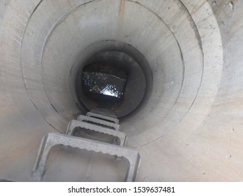 looking down concrete manhole from street level